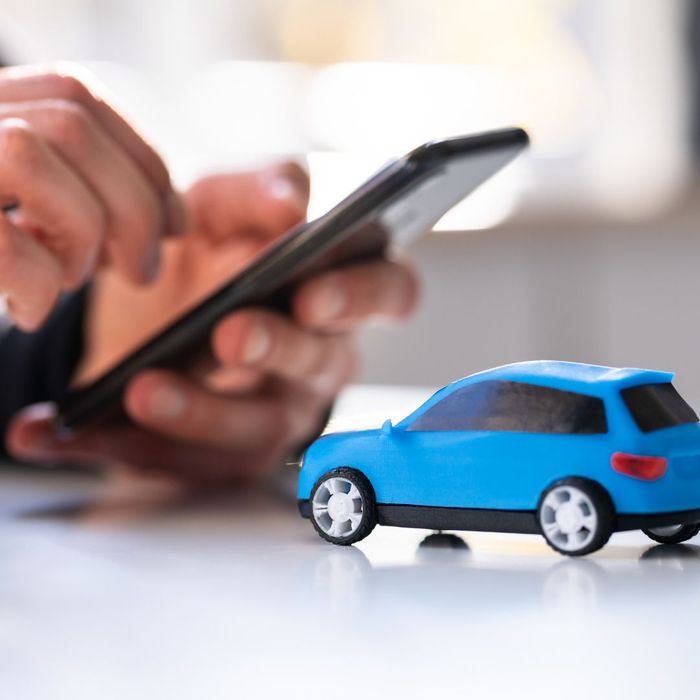 persons hands holding a cell phone with a toy car near by