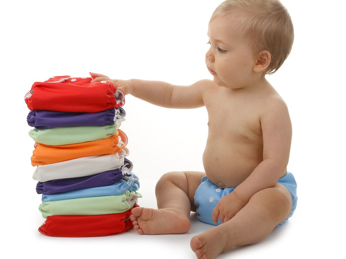 Baby looking at a stack of cloth diapers from Bum Baby Bum.