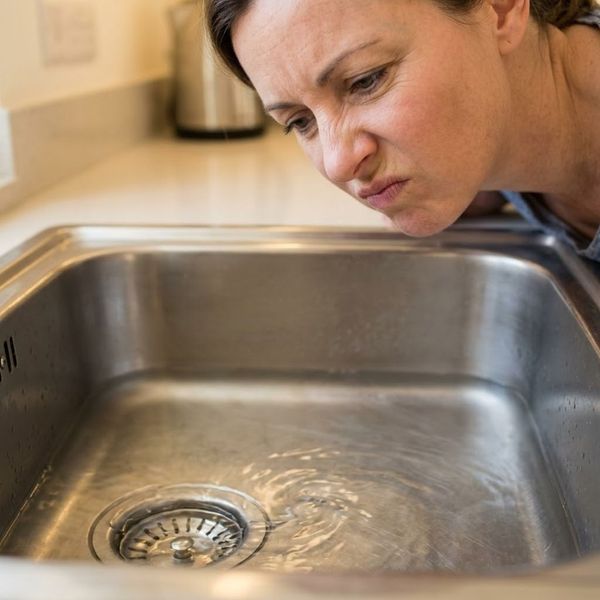 A close-up view of a homeowner observing a slow-draining sink in her kitchen.
