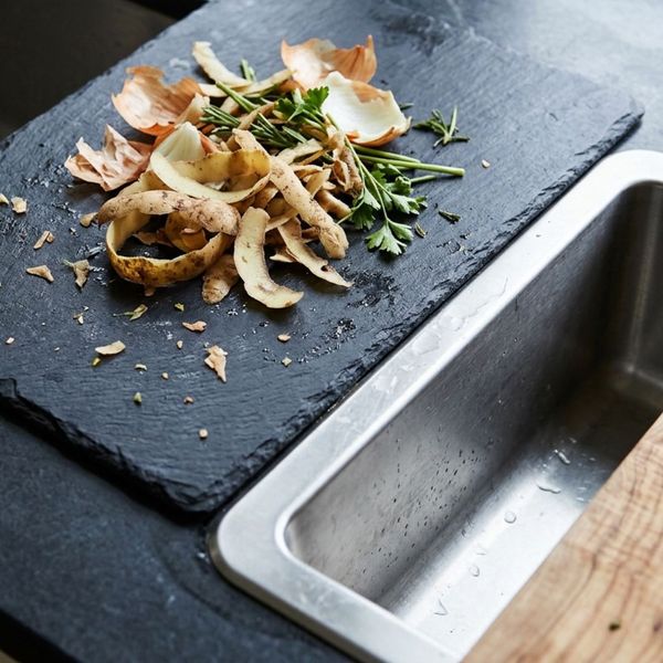 Vegetable peels and organic food scraps set aside on a prep board instead of going into the sink drain.