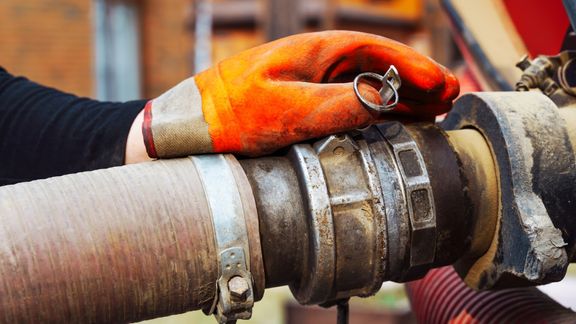 A professional pumping a septic tank in a rural setting. A professional pumping a septic tank in a rural setting.