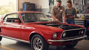 Classic car in a garage with owner working Classic car in a garage with owner working