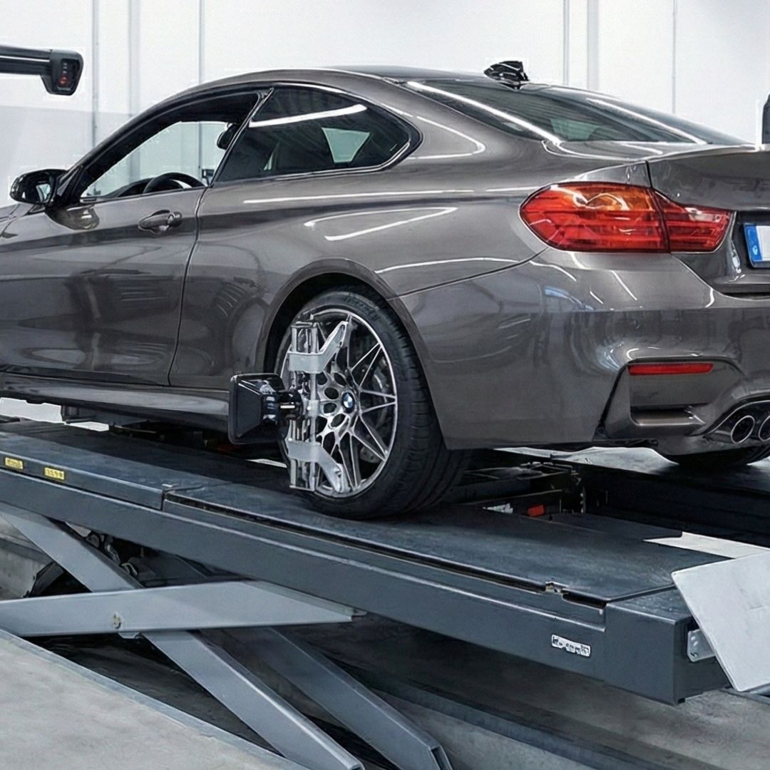 premium import sports car undergoes a precision wheel alignment on specialized automotive equipment.