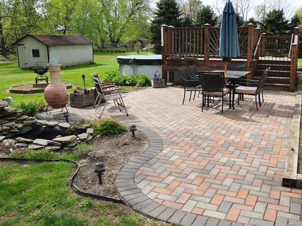 An image of a backyard patio designed with multi-colored paver bricks  