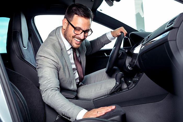 man happily rubbing the seats of his new car