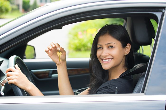 A happy woman in a car holding the key