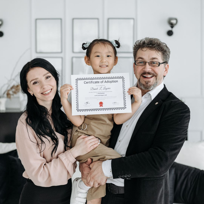 parents holding daughter who has a certificate of adoption parents holding daughter who has a certificate of adoption