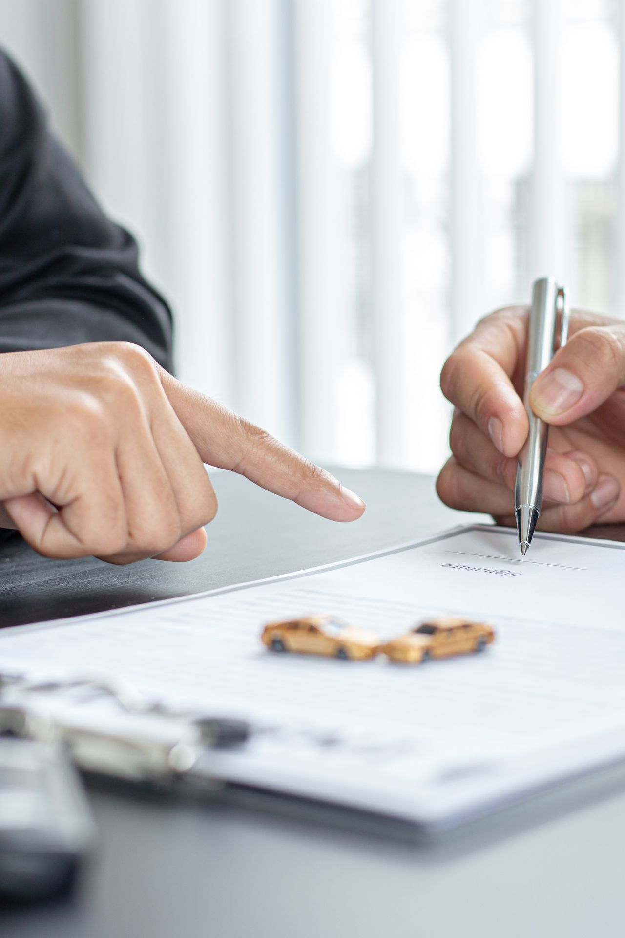 two professionals working on a contract with toy cars on top of the papers