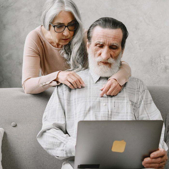 elderly couple composing list on computer 