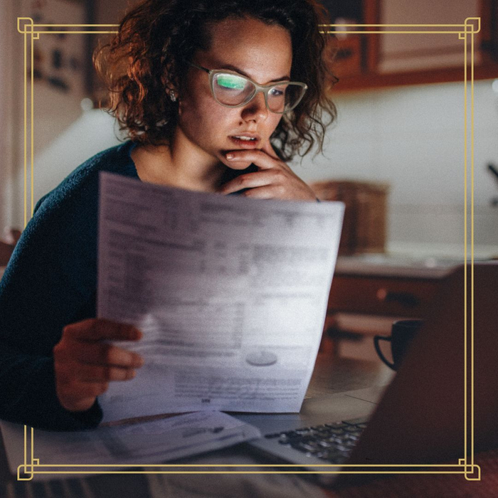 Person looking at a laptop screen while holding a financial document