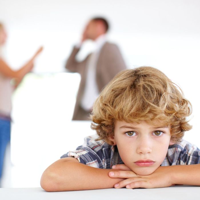 A kid looking sad with arguing parents in the background