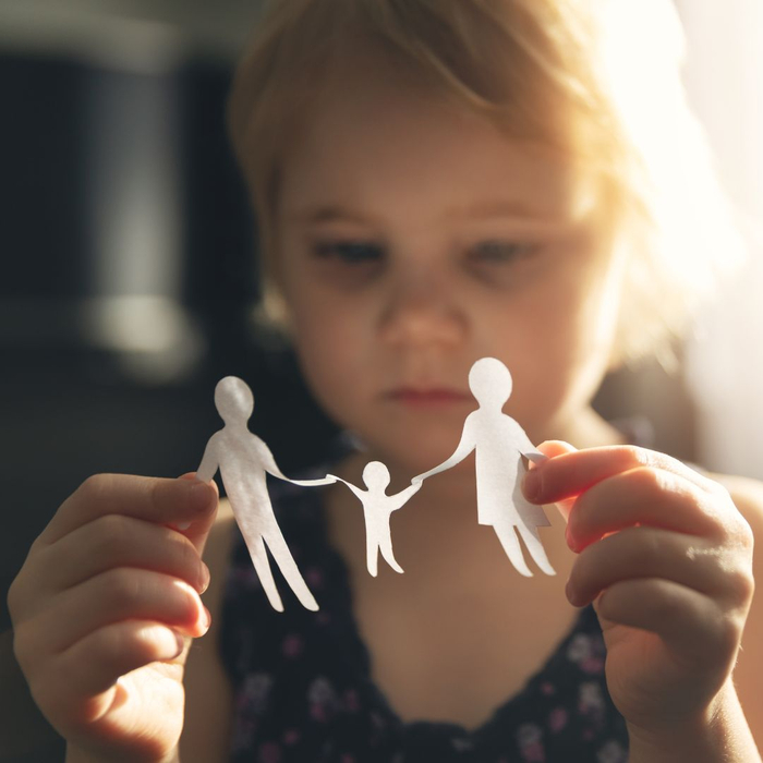 Child plays with a paper family looking sad