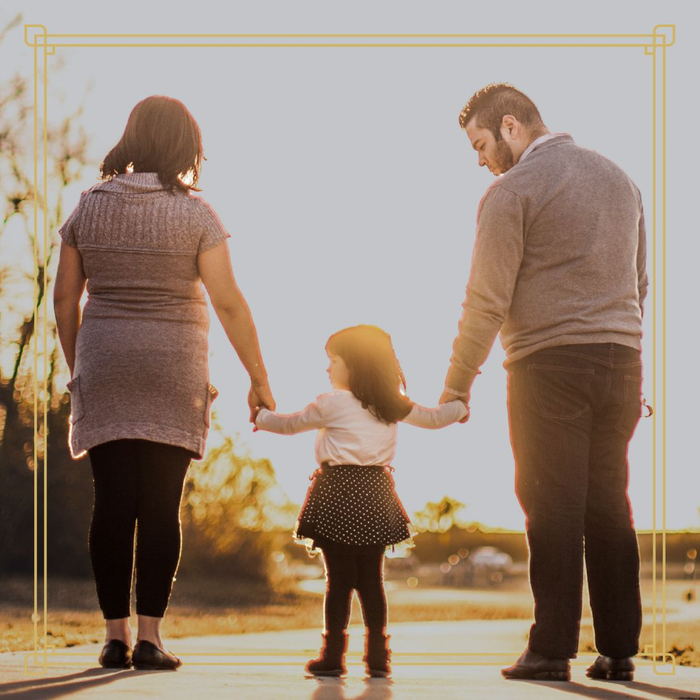 Two parents holding the hands of their child