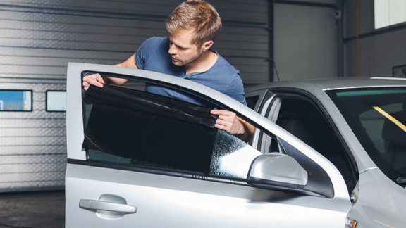 man applying car window tint