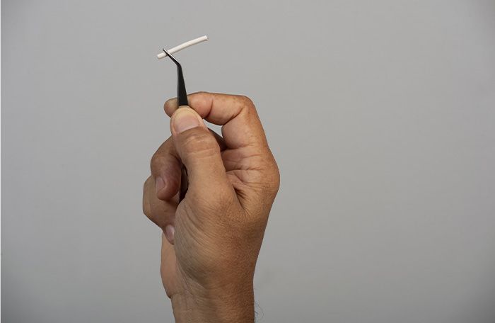 holding up birth control implant with tweezers