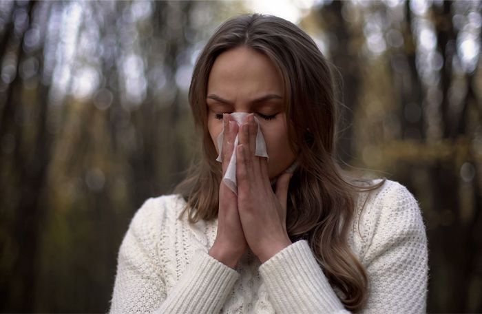 woman sneezing outdoors