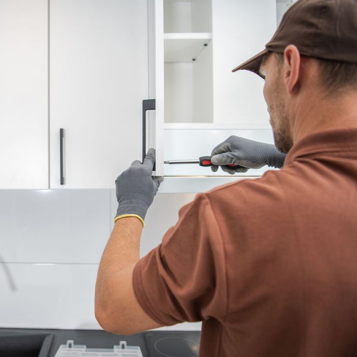 man screws in handles on a kitchen cabinet