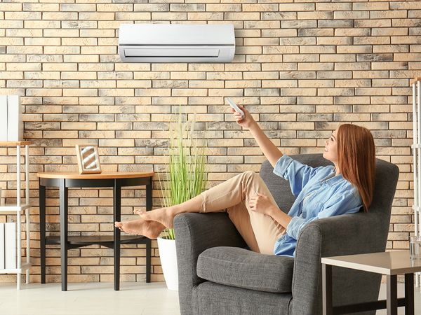 woman using a remote to turn on her mini-split air conditioner