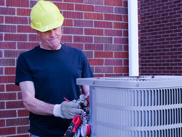 Heating and Cooling technician repairing AC unit