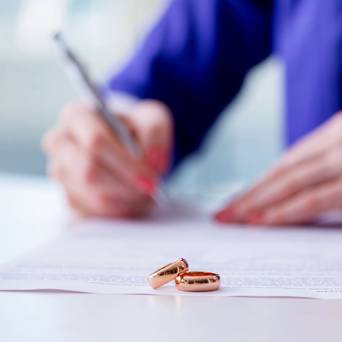 signing a document with wedding rings nearby