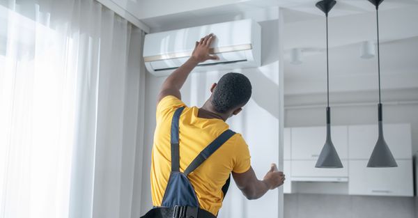 A HVAC technician installs a wall-mounted air conditioner