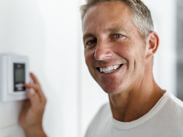 Smiling man adjusting thermostat