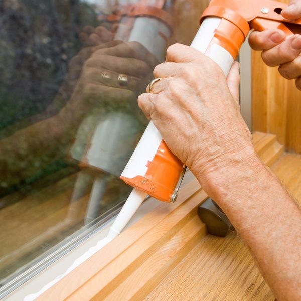 man caulking window gaps