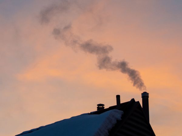 Snow covered roof with smoking chimney