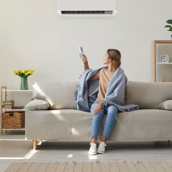 person on couch controlling HVAC system with remote