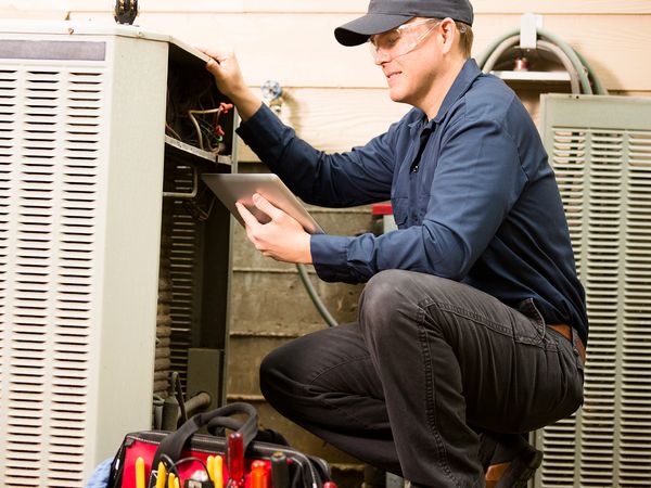 HVAC technician servicing air conditioner unit