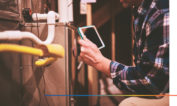 repairman inspecting a furnace with a tablet in hand