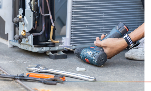 repairman drilling into an A/C unit