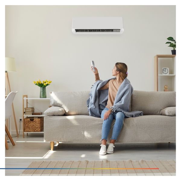 Person sitting on the couch controlling the AC with a remote