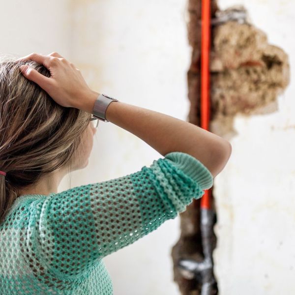 woman looking at water damage from burst pipe