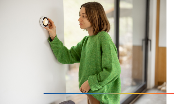 Woman changing smart thermostat in house