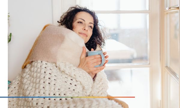 Person wrapped in a blanket while holding a mug