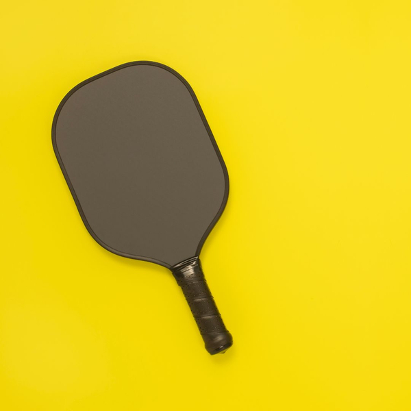 bright yellow background with black pickleball paddle