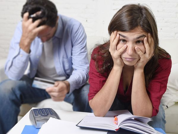 Man and woman with bills and a calculator looking stressed out.