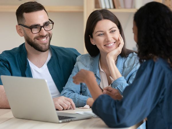 Real estate agent helping a couple who are happy after eliminating debt with a short sale on their home.