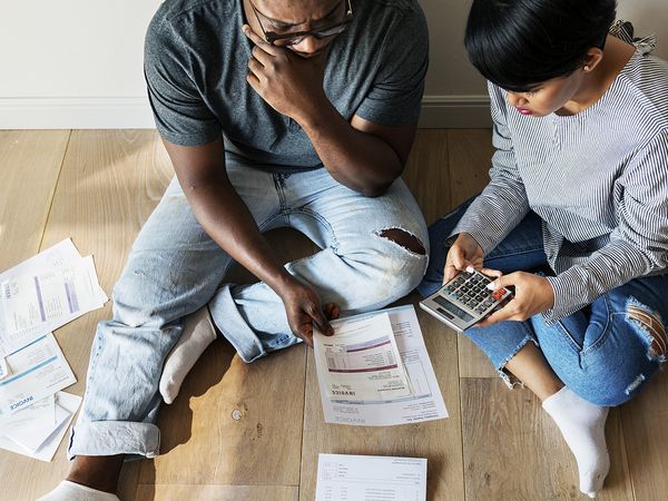 Stressed out man and woman sitting on the floor surrounded by billing statements