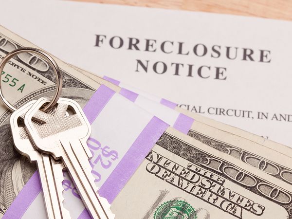 House keys on a stack of money on top of a foreclosure notice.