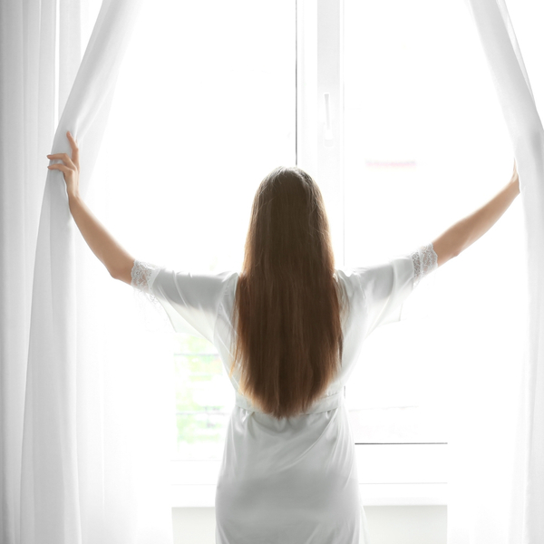 Woman opening curtains, letting light in
