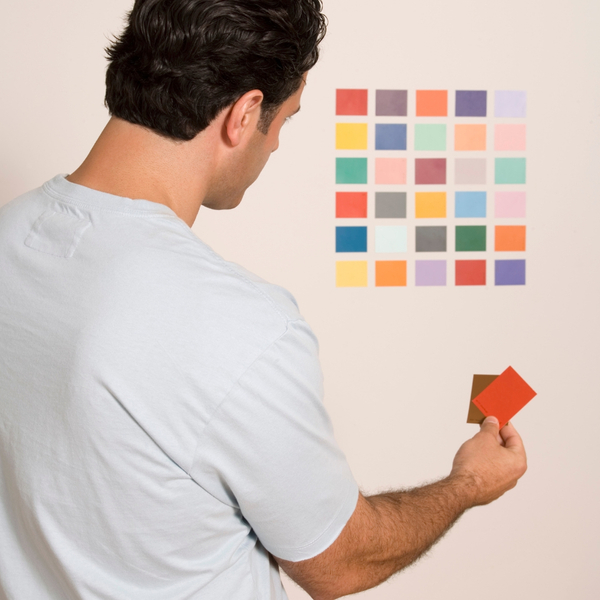 man studying paint chips on wall