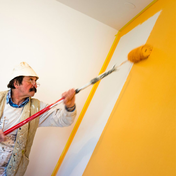 man painting wall yellow