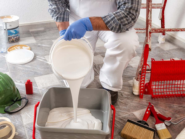 Professional painter pouring white paint into tray