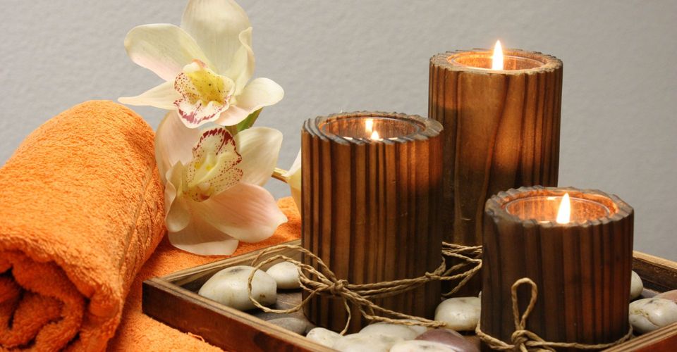 Lit candles on a table with flowers and twine.