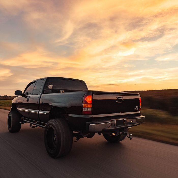  A black pickup truck driving into the sunset