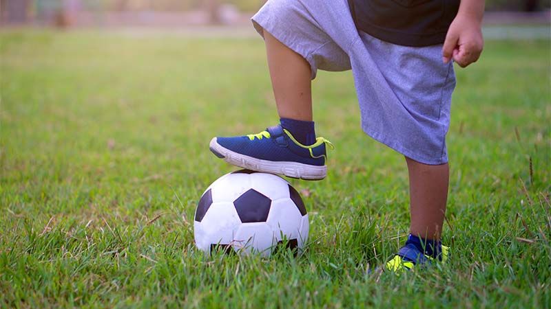 kid with foot on soccer ball
