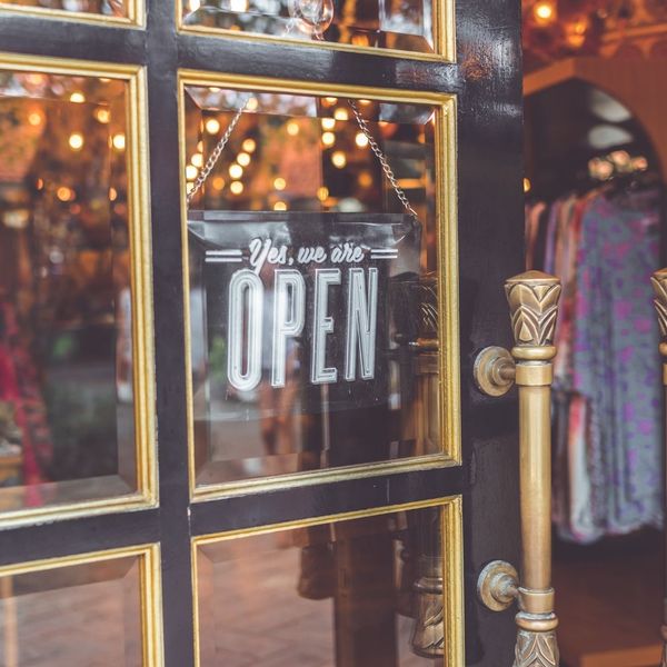 "yes we are open" sign on gold-and-black small business door