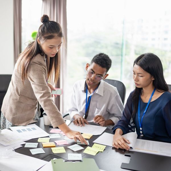 three coworkers organizing several sticky notes on meeting desk